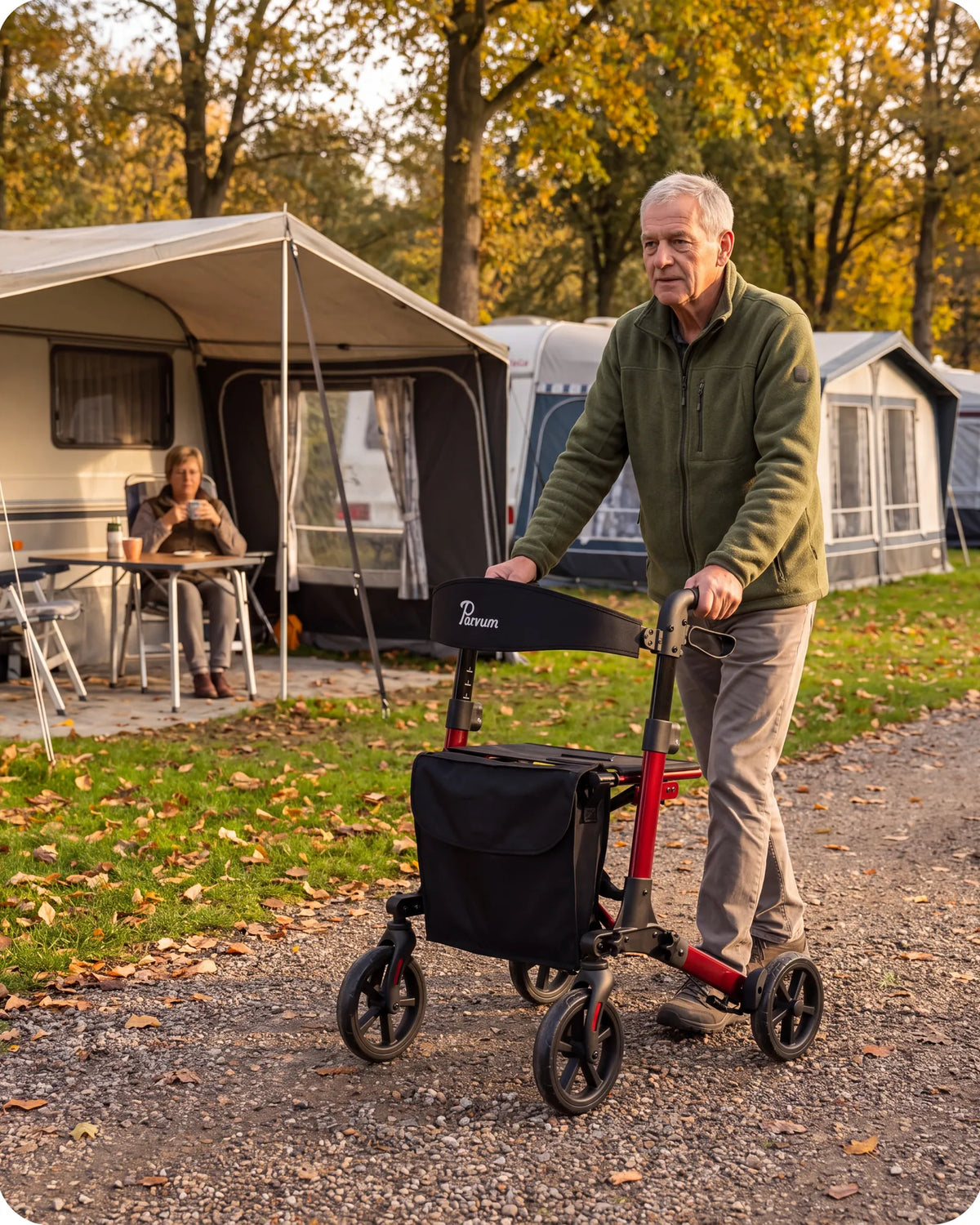 Parvum Brava in ruby red at a campsite in autumn; a man walks with the rollator between the caravans.