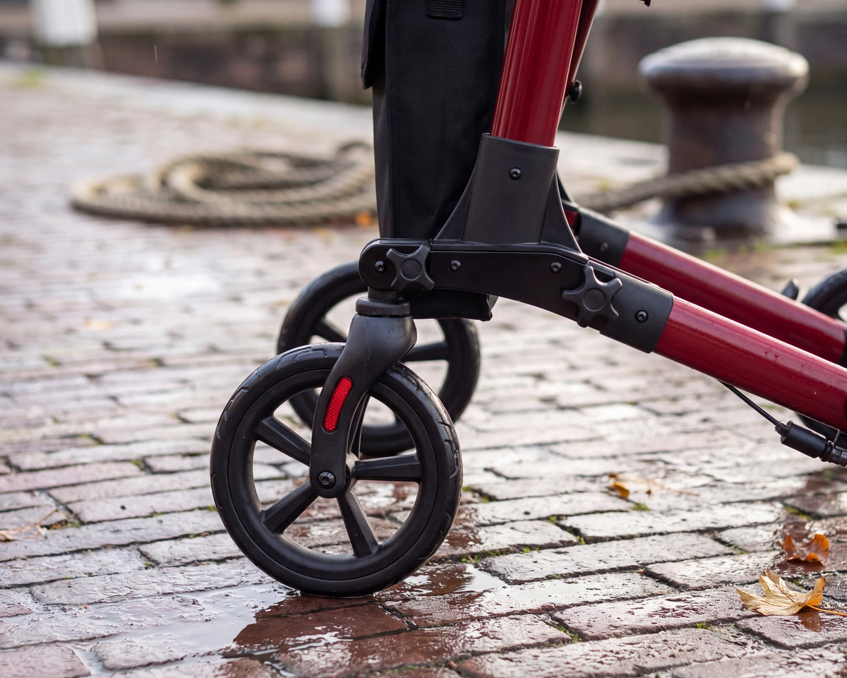 Close-up of the front wheel of the Parvum Brava in ruby red on the wet cobbles of a quay.