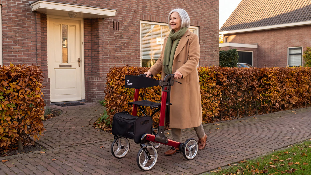 Parvum Luxo in robijnrood; een vrouw in een camel jas stapt met de rollator de voordeur uit, langs een beukenhaag.