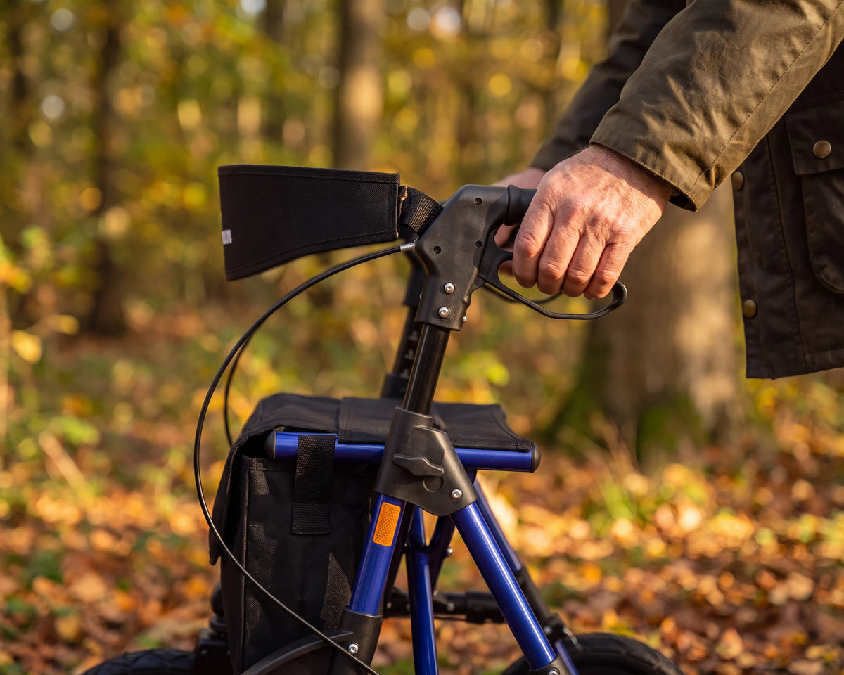 Een hand op het handvat en de remhendel van de Parvum Rebel in blauw in een herfstbos.