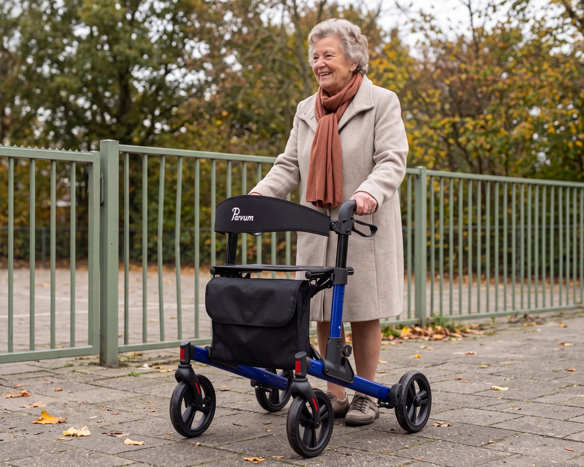 Parvum Riva in blauw bij een schoolhek; een vrouw met grijze krullen lacht, haar handen op de handvatten.