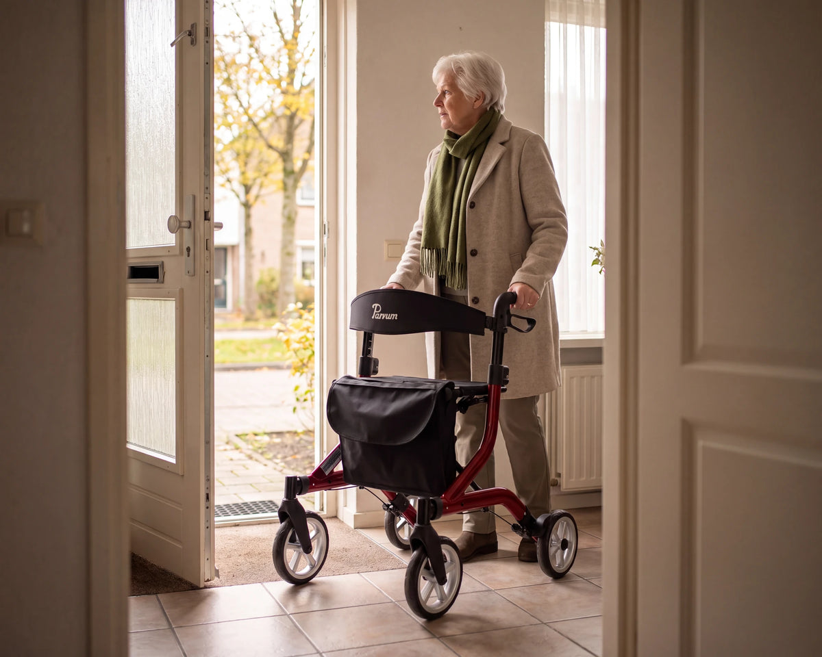 Parvum SuperLight in rood in de hal bij de open voordeur; een vrouw staat klaar om naar buiten te gaan.
