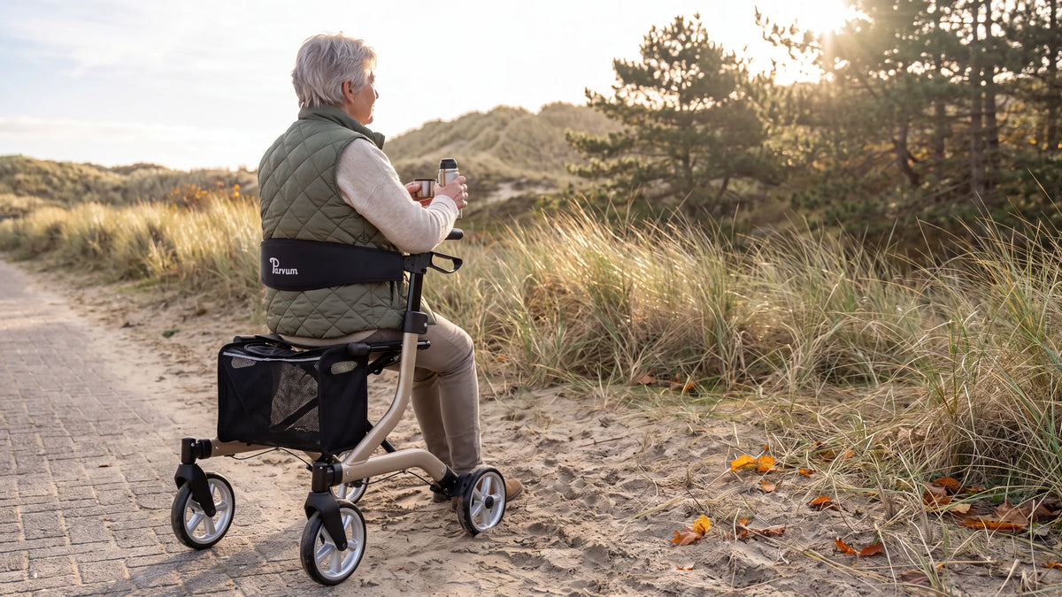 Parvum SuperLight Plus in champagne at the edge of the dunes against the light; a woman sits on the rollator with a cup of tea.